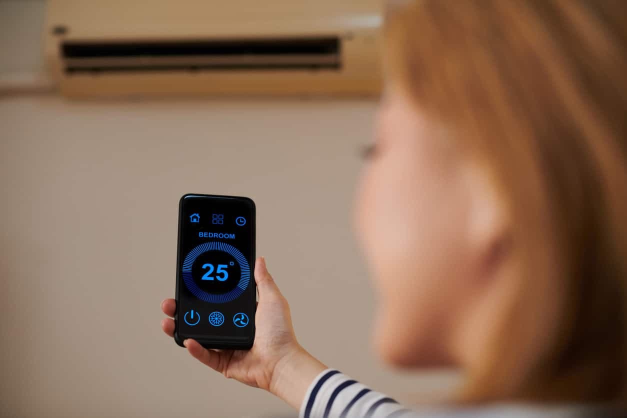 Bilde av en dame som styrer en smart varmepumpe med WiFi ved bruke mobilappen.