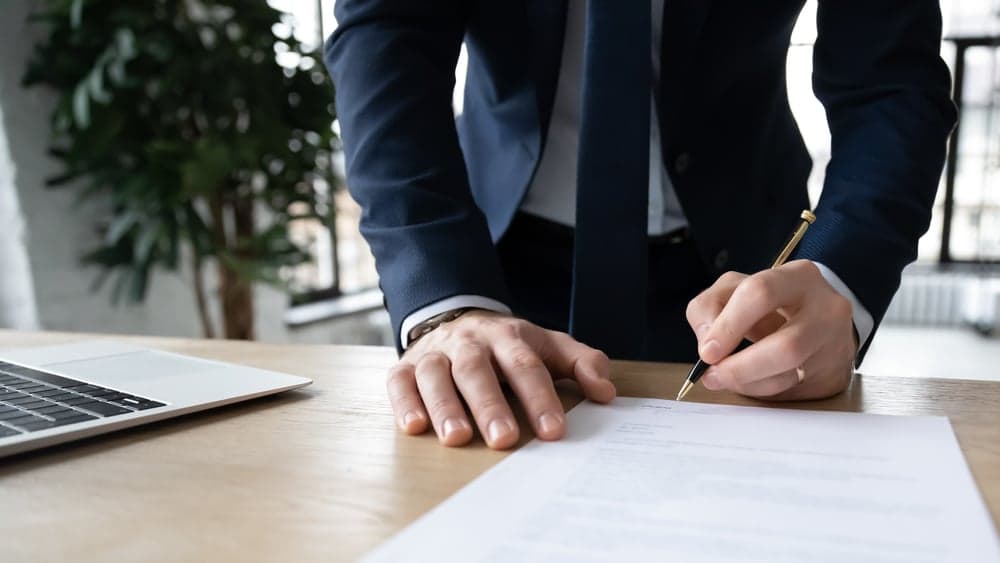 bilde av mann som signerer et dokument, brukt som illustrasjon i artikkel om boligsalgsrapport.