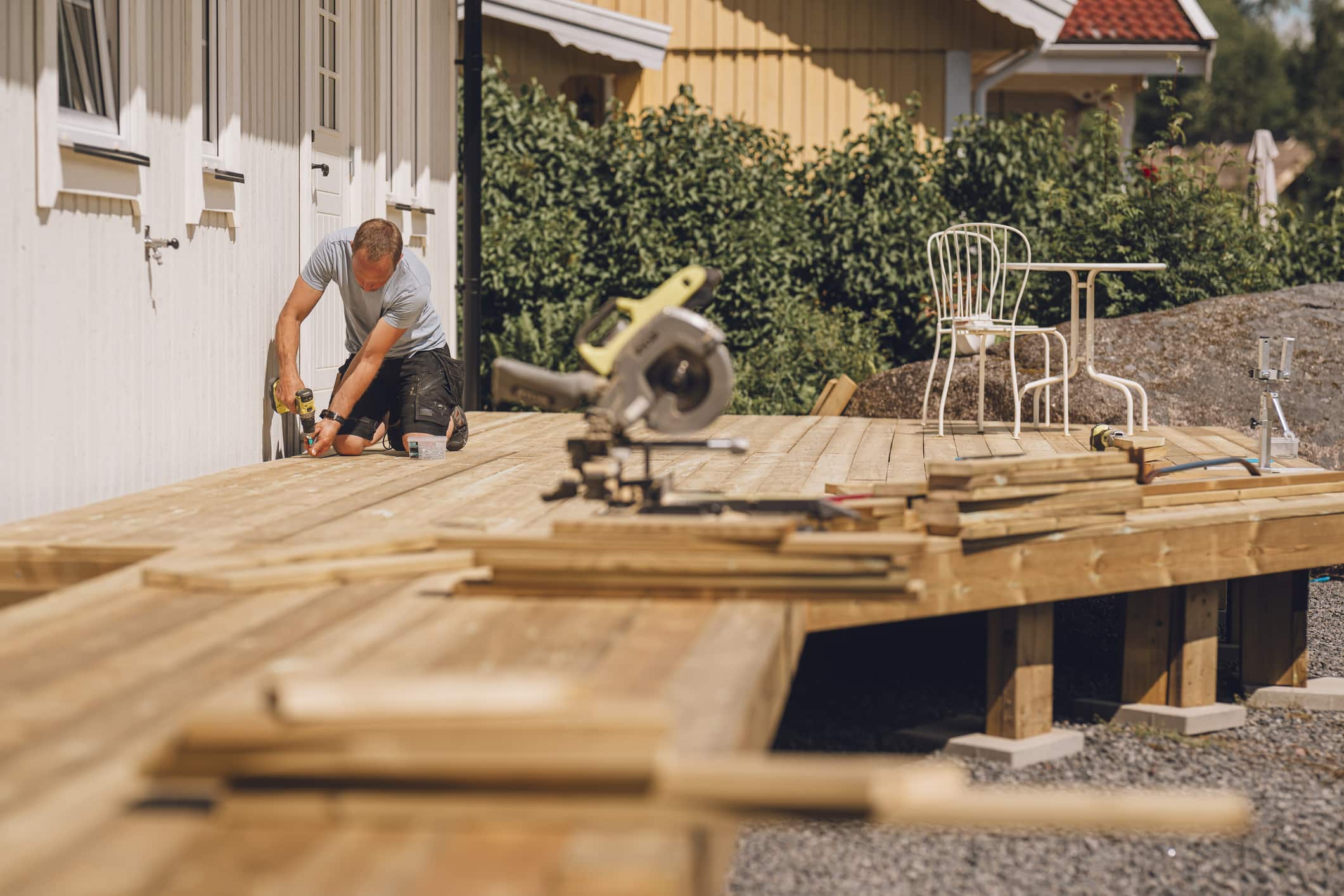 Profesjonelt firma bygger terrasse ved hvitt bolighus.