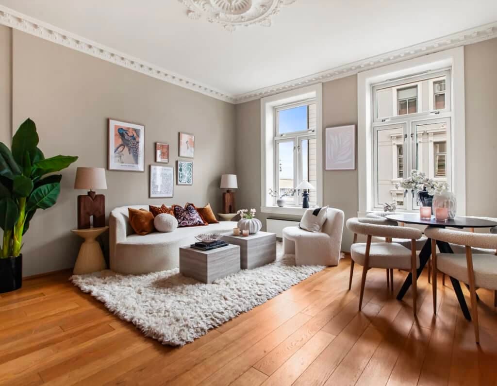 Elegant stue med høye vinduer og stukkatur ferdig stylet.